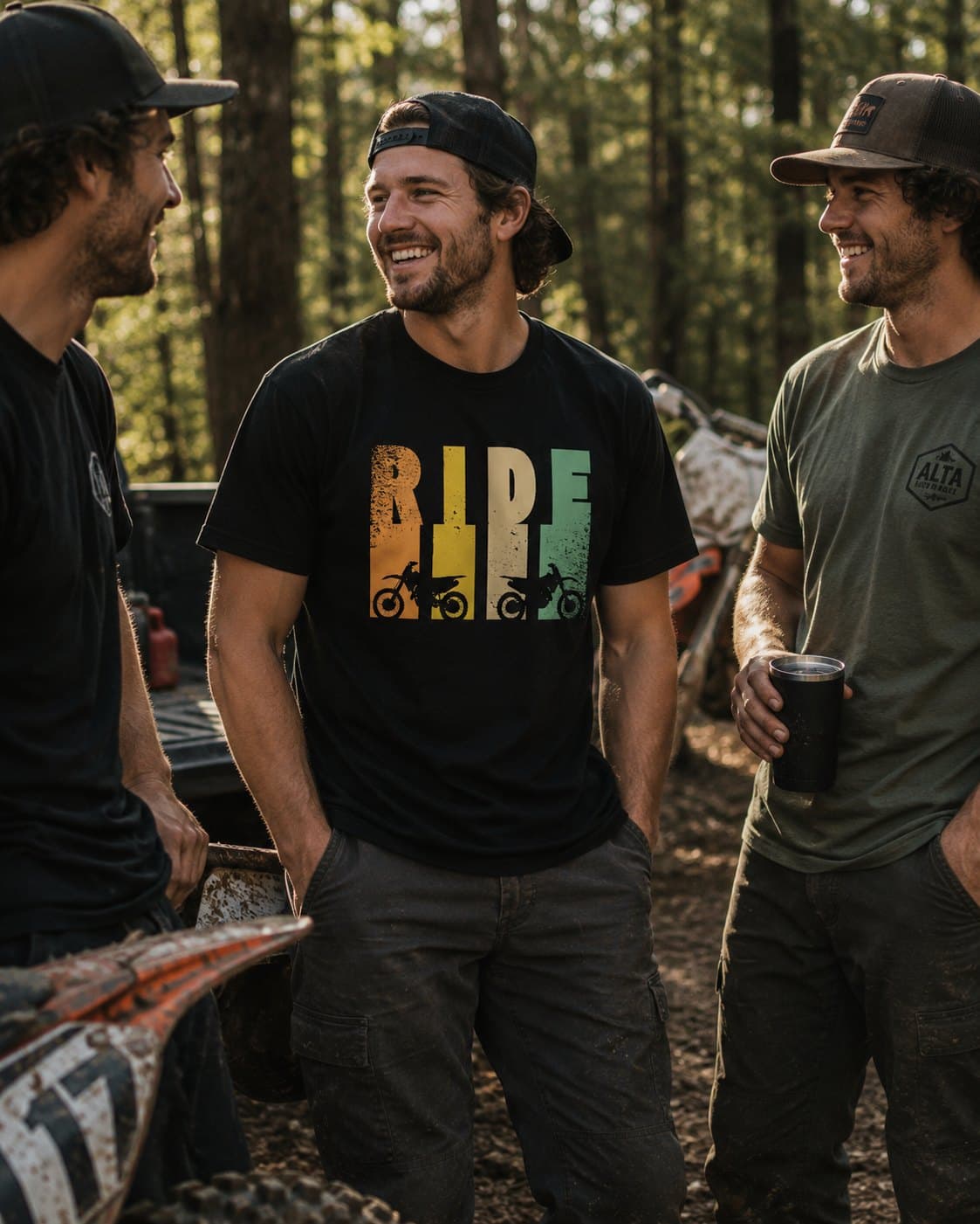 Three riders laughing at the trailhead, the middle rider wearing the black RIDE tee with a retro striped dirt bike graphic